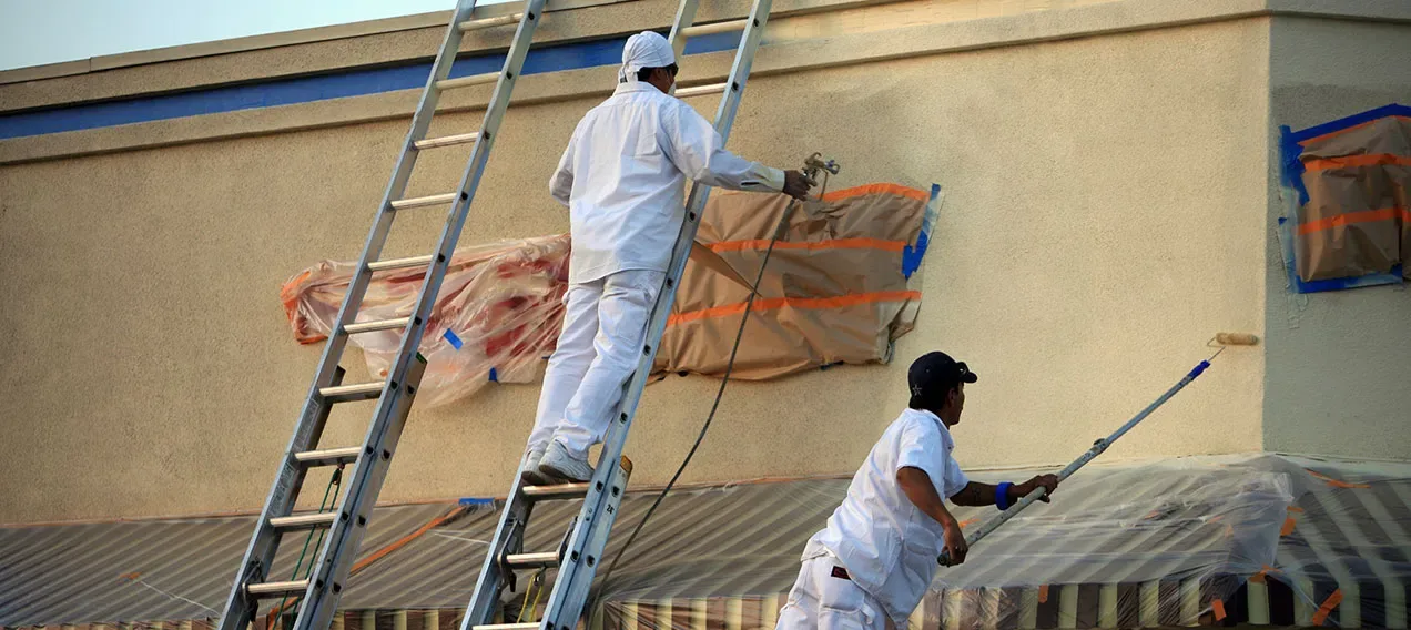 Painting contractor applying exterior paint to a building wall